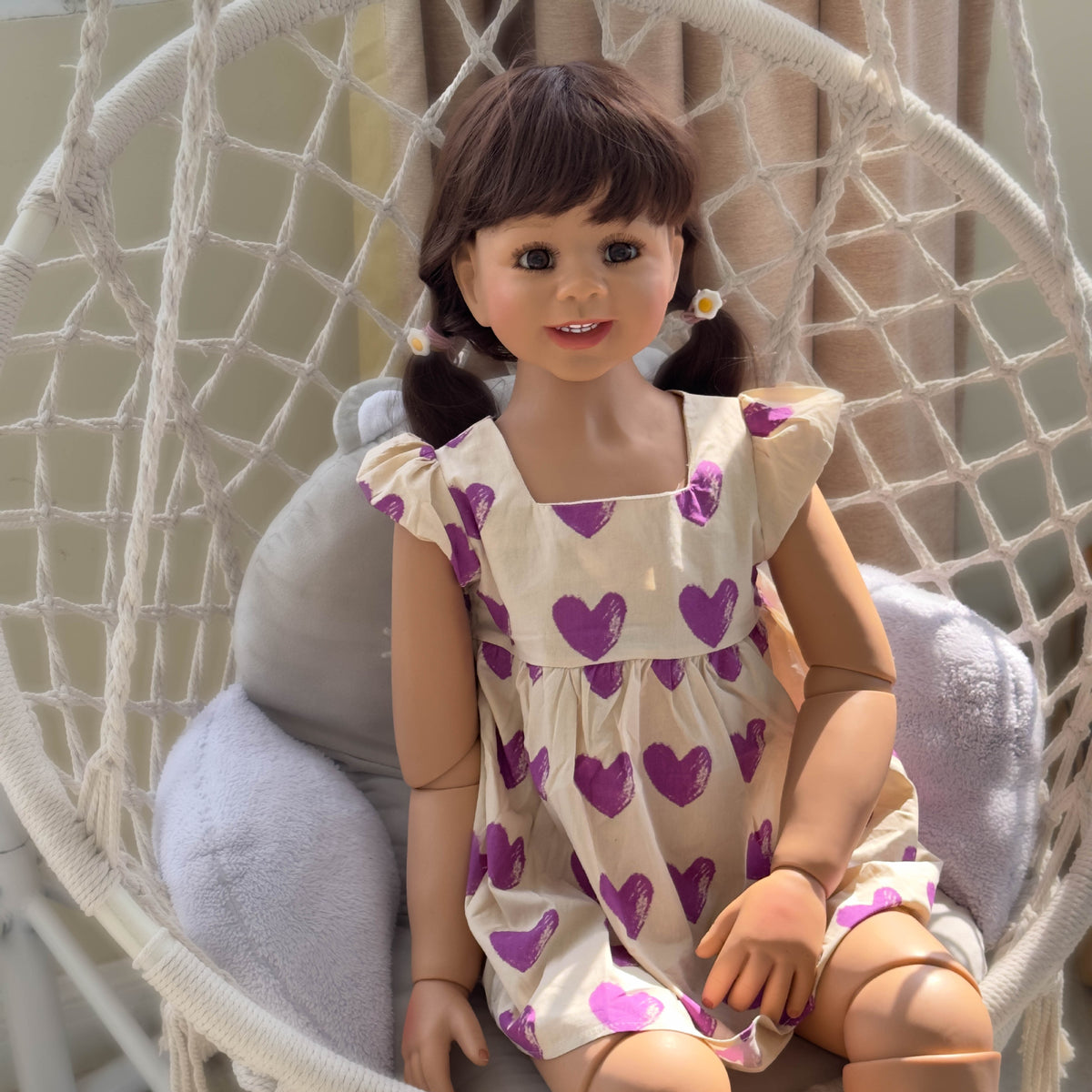 Muñeca Reborn de pie para niños pequeños, tamaño real (43 pulgadas), con cuerpo completo de vinilo; viste un vestido morado con estampado de corazones y mangas con volantes. 