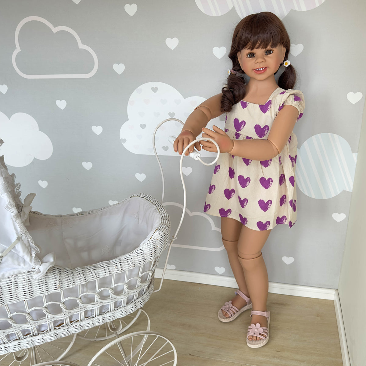 Muñeca Reborn de pie para niños pequeños, tamaño real (43 pulgadas), con cuerpo completo de vinilo; viste un vestido morado con estampado de corazones y mangas con volantes. 
